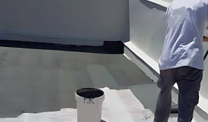 Hombre aplicando material de impermeabilización de cubiertas en una terraza